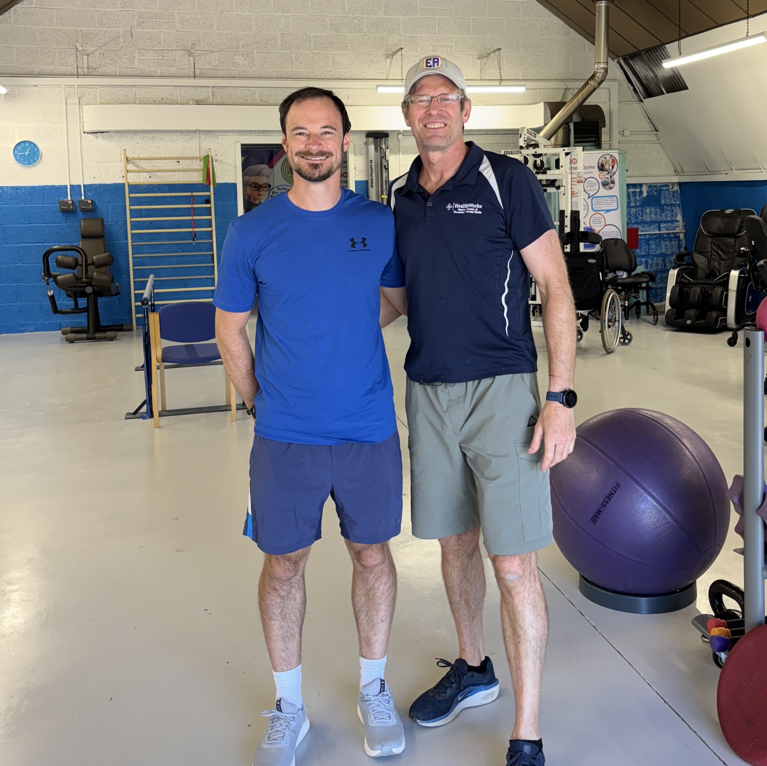 Matt Brinkley from Making Fitness Accessible and Alan Pearson from HealthWorkz standing together in the accessible therapy gym, showcasing their collaborative partnership in neurological fitness and chronic health conditions
