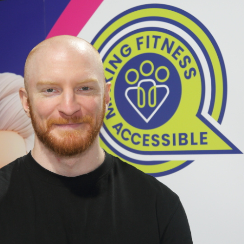 Peter, Inclusive Exercise Coach at The Angel Centre, smiling in front of Making Fitness Accessible logo
